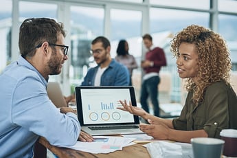 Man and woman talking in front of laptop